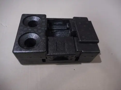 Schwarzes Isolationsmodul von Remeha mit zwei Vertiefungen und einer zusätzlichen Fläche, auf Untergrund liegend. Geometrische Form ohne erkennbare Maße.